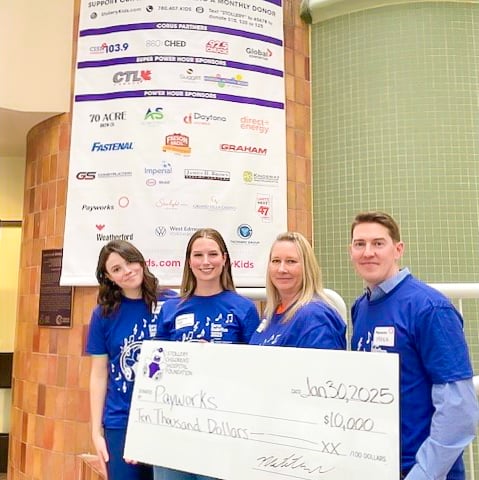 Quatre personnes en chandail bleu tiennent un chèque géant de 10 000 $ remis par Payworks à la Fondation de l’Hôpital pour enfants Stollery.