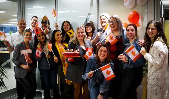 A large team of Payworks employees waving Canadian flags. 
