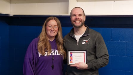 A person receives a “Heart of a Champion” certificate in an arena locker room.