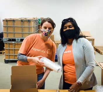 Two Payworks staff unpacking a box. 