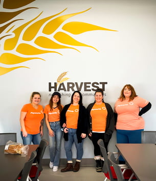 Cinq employées de Payworks devant un panneau Harvest Manitoba. 