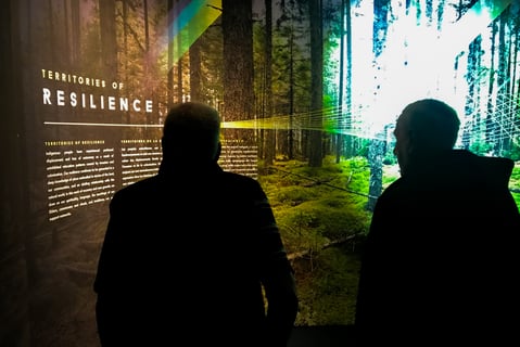 3.	Deux personnes debout devant une exposition qu’elles sont en train de lire 