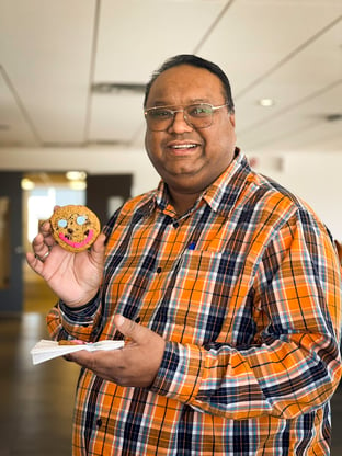 A Payworks staff in the office holding a Tim Hortons Smile Cookie.