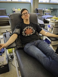 A Payworks staff sitting in a large chair donating blood.