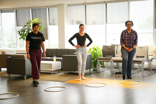 Three staff standing in front of hoops.