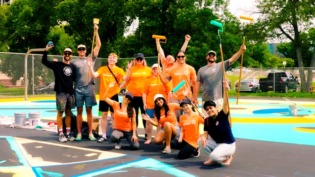 Eight Payworks staff in matching orange t-shirts with three members from Buckets & Borders.