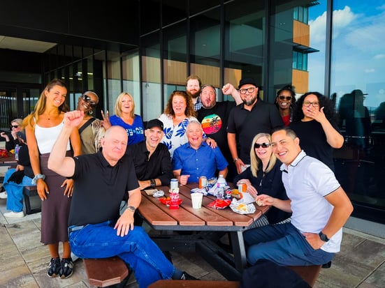 A group of Payworks staff enjoying lunch at a picnic table on an office patio. 