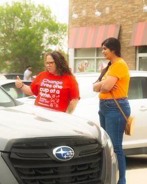 Two Payworks employees talking to guests in the Tim Hortons drive through to raise awareness for Camp Day. 
