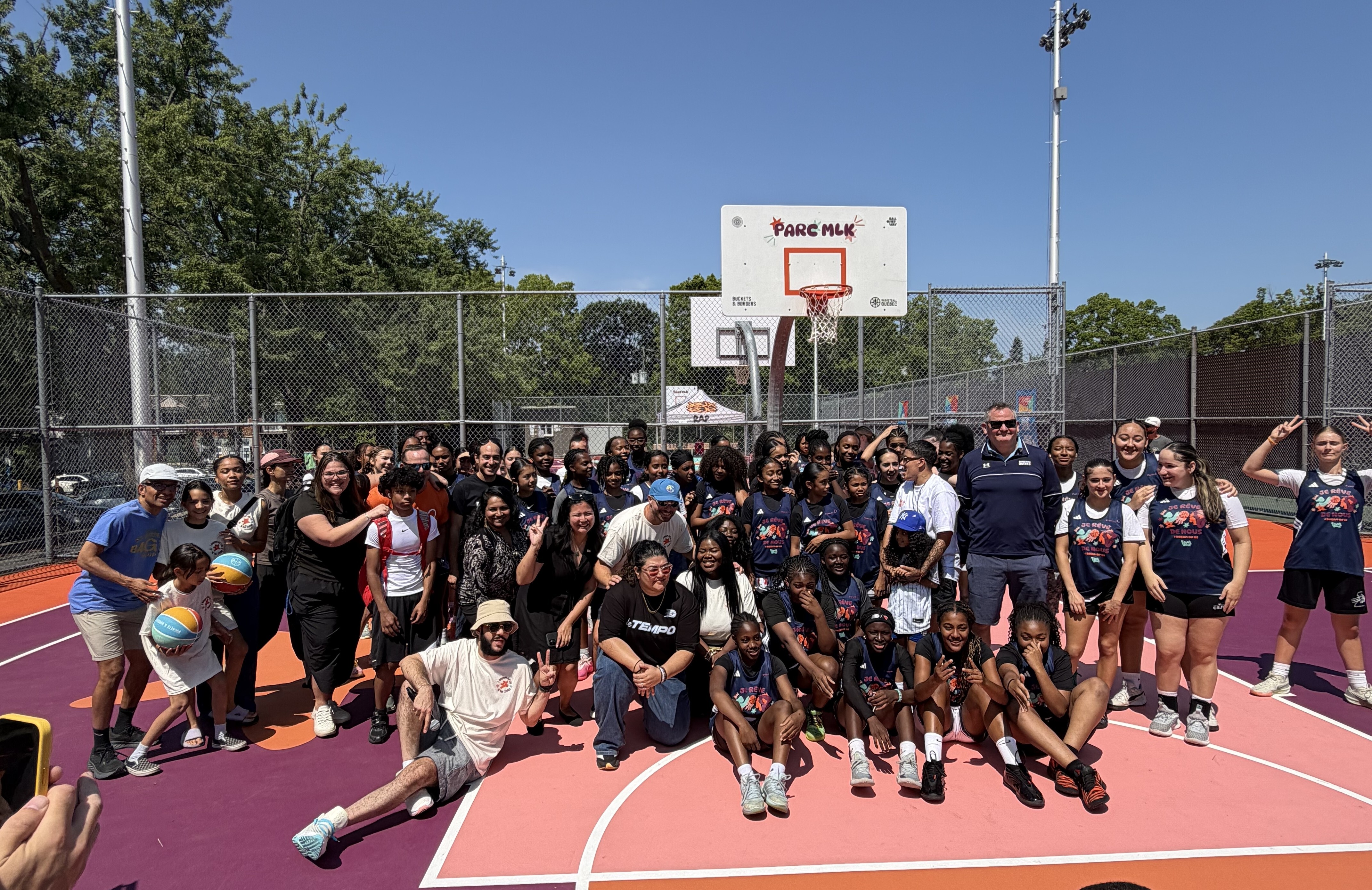 Local community members – including local female youth basketball teams – pose at for a Grand Opening photo on the newly renovated court. 