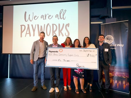 Six individuals holding a giant cheque for $5,000.