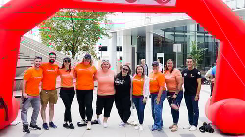 4.	Ten Payworks staff under an inflatable archway at an outdoor event.