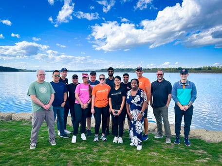 Fourteen Payworks staff standing in front of a lake. 