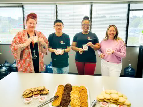 5.	Four Payworks staff holding cookies behind a table filled with sweet treats.