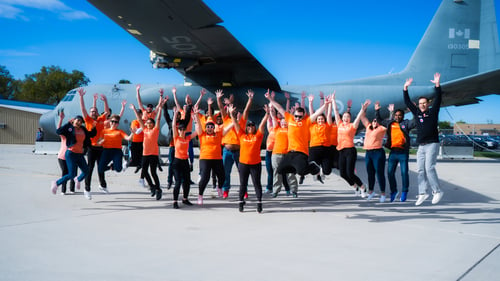 Un groupe d’employés de Payworks sautant en l’air devant un avion en stationnement.