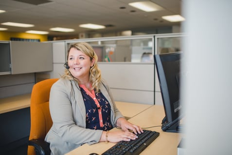 Customer service representative working at a cubicle with a headset on. 