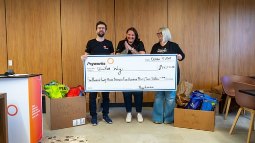 2.	Three Payworks staff holding an oversized cheque and surrounded by donation boxes.