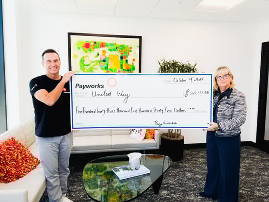 Payworks Past President & CEO JP Perron and Co-Founder Barb Gamey hold a giant donation cheque for United Way in 2024.