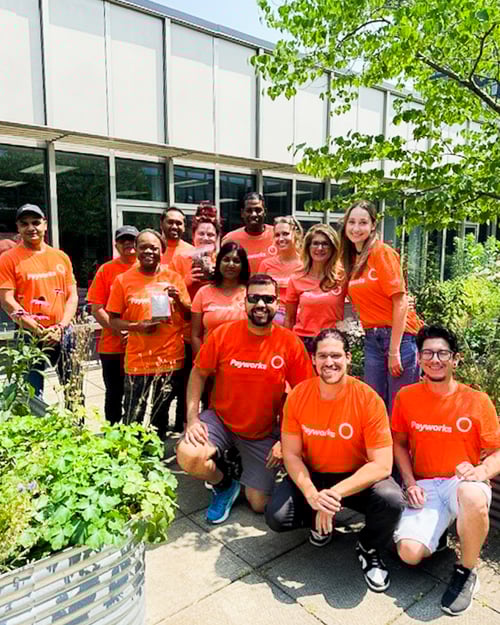 A group of 13 Payworks staff in matching orange t-shirts outside the Toronto Humane Society. 