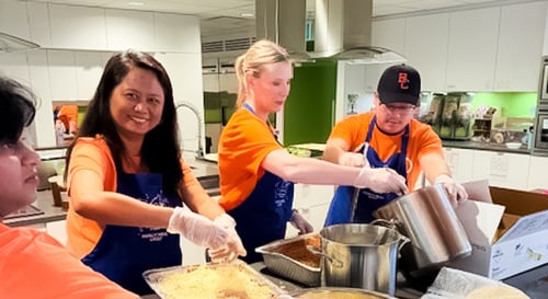 Four Payworks staff prepping a meal at a kitchen counter.