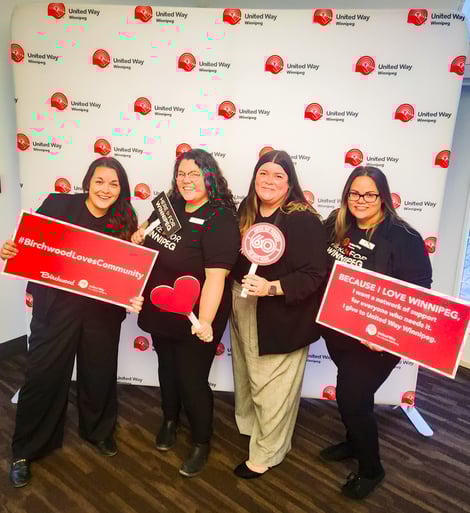 Four United Way Sponsored Campaign Associates holding United Way signage in front of a United Way backdrop.
