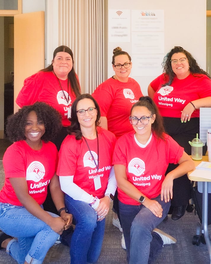 Six United Way Sponsored Campaign Associates seated in an office and smiling for the camera.