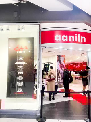 2.	Une devanture de magasin avec une enseigne rouge indiquant « aaniin » et trois clients à l’intérieur.