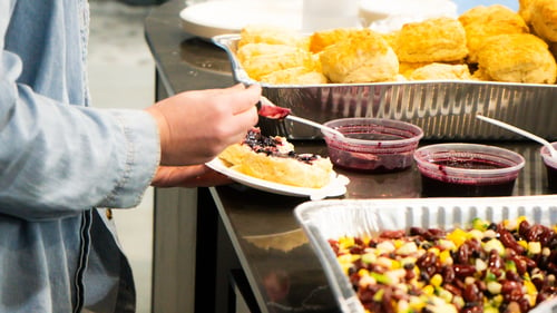 A Payworks staff member serving themselves bannock, jam and three-bean salad.