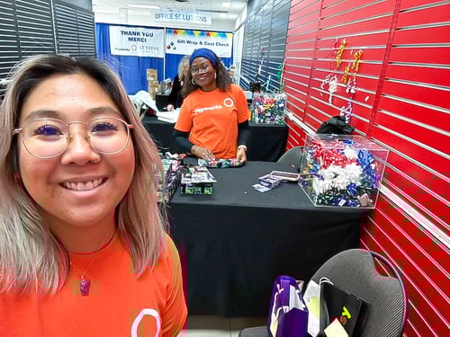 Two Payworks staff in matching orange t-shirts at gift wrapping stations. 