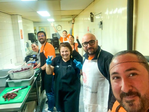 A team of Payworks staff chopping food in a galley kitchen.
