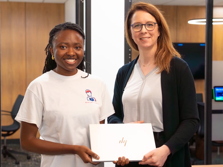 Two people holding a laptop in an office.