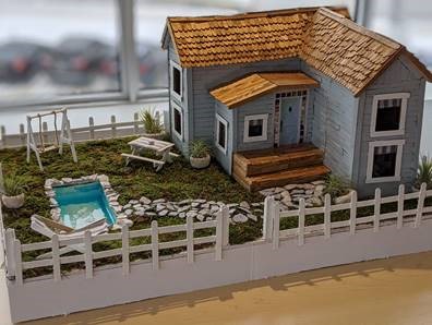 Popsicle stick house with yard and pool.