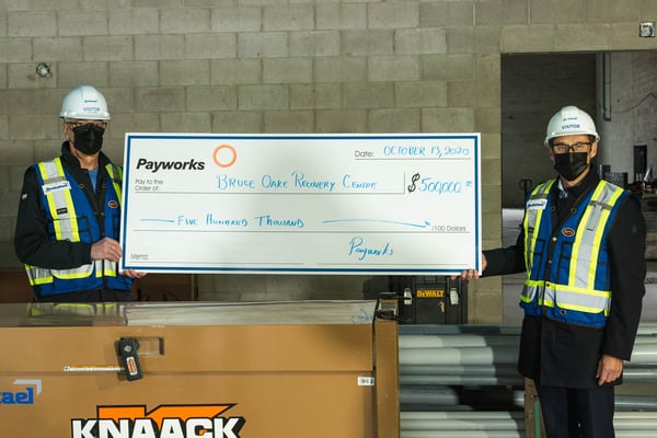 Two individuals holding a large cheque.
