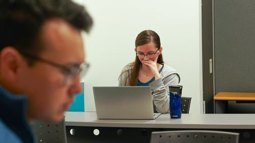 A Payworks staff looking at a laptop computer with their hand rested on their chin. 