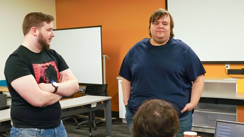 Two Payworks staff standing and discussing with another staff who is sitting down. 