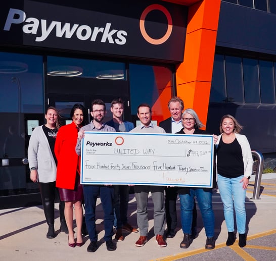 Eight individuals holding a giant cheque.