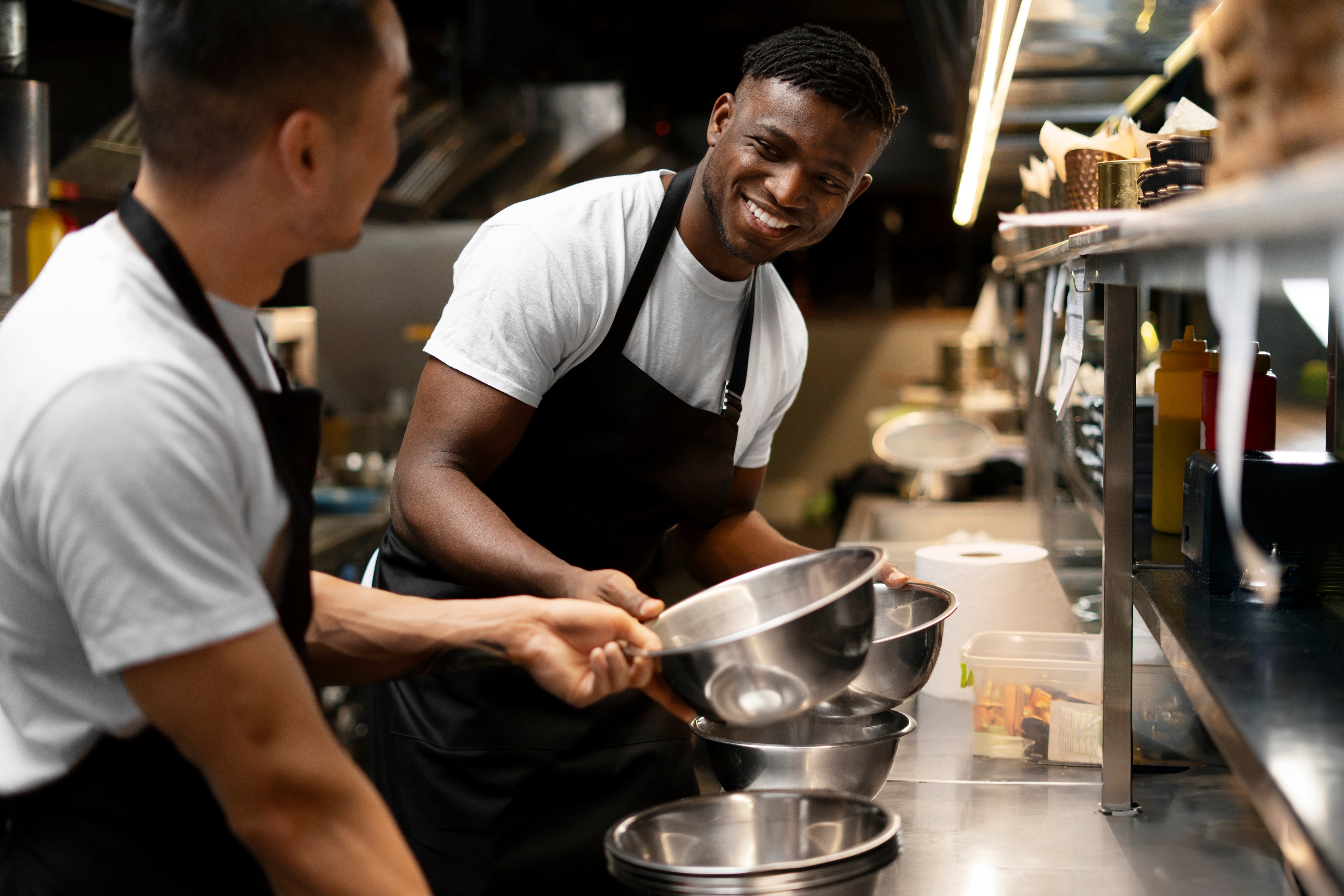 Deux chefs cuisiniers portant des tabliers travaillent dans une cuisine.