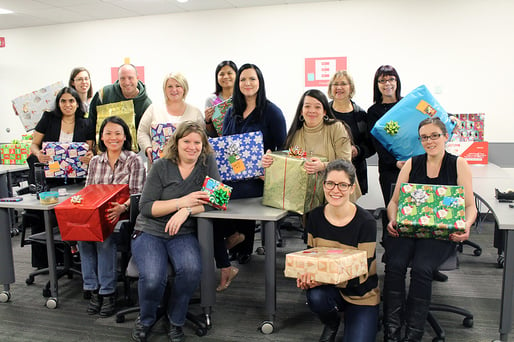 Thirteen individuals holding presents.