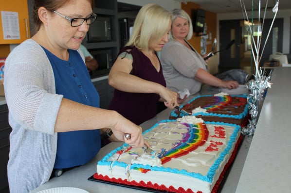 Three Payworks staff cutting cake.