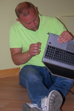 Kevin Sokolowski sitting on the ground fixing a laptop computer.