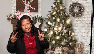 An individual in front of a holiday tree. 