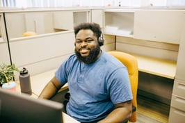 PayworksStock_-	A Service staff member seated, smiling and wearing a telephone headset. 