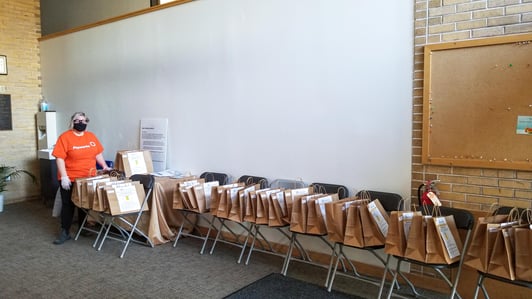 Payworks Technical Writer Rachel Wolman standing at the far end of a long line of chairs with gift bags on them. 