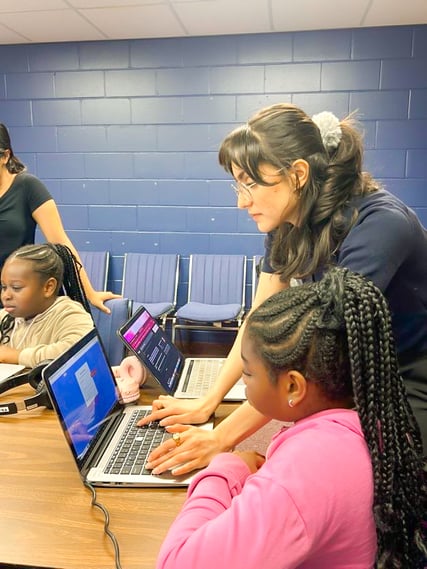 An instructor showing a student how to complete a task on a laptop. 