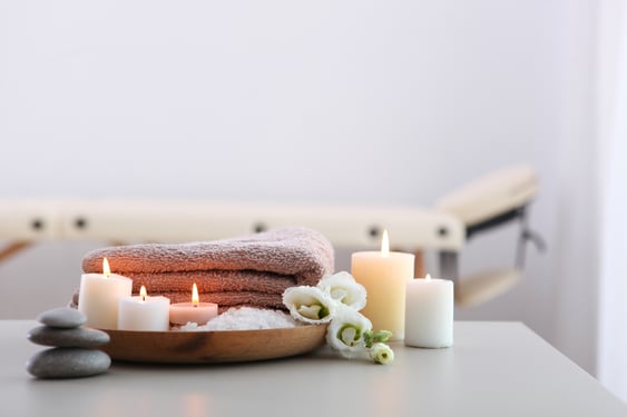 A massage/wellness table with candles and towels on a table.