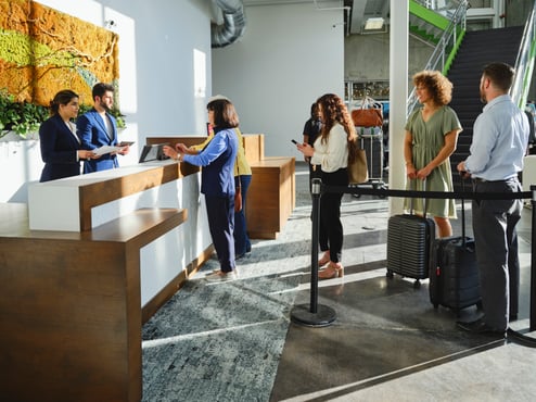 A line up of four people checking in to a hotel.