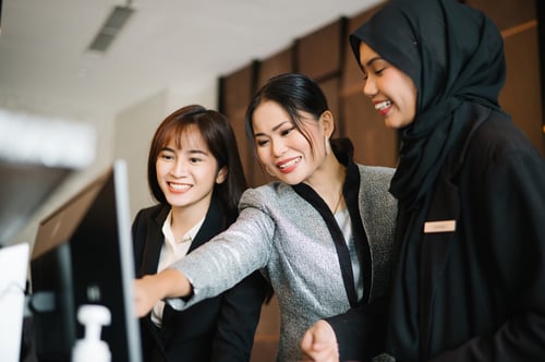 Trois employés de l’hôtel, l’un d’eux pointant un écran d’ordinateur.