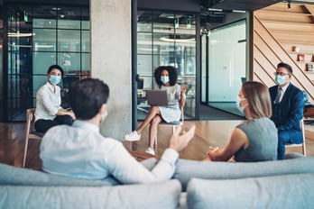 A group meeting with individuals wearing masks.