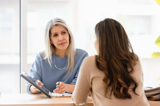 Une superviseure utilise une tablette pour partager des informations avec une employée.