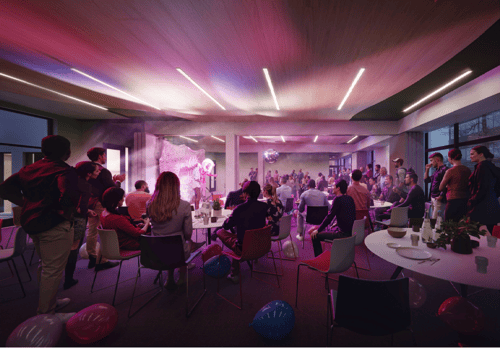 Performers on stage in a darkened multi-purpose space filled with a diverse audience.