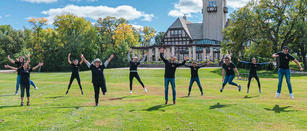 10 Payworks staff jumping in a park. Text reads, “Pay it Forward”.  